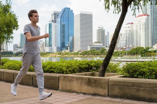 Jeune bel homme jogging dans le parc