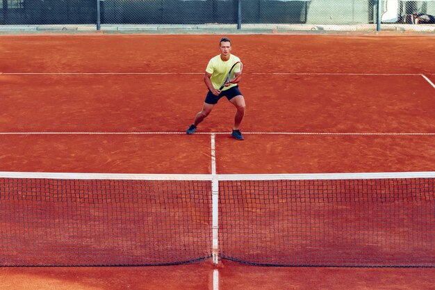 Jeune bel homme jouant au tennis sur le court de tennis