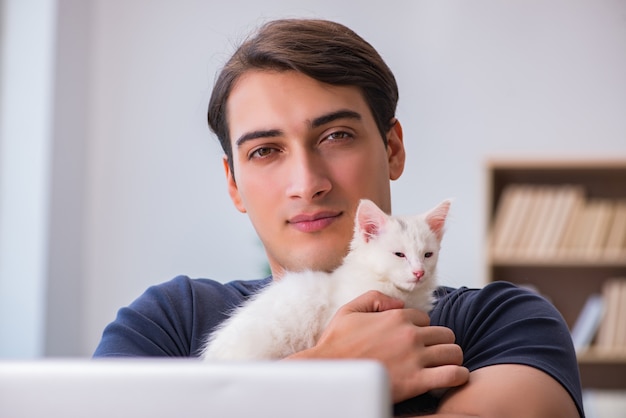 Jeune bel homme jouant avec un chaton blanc