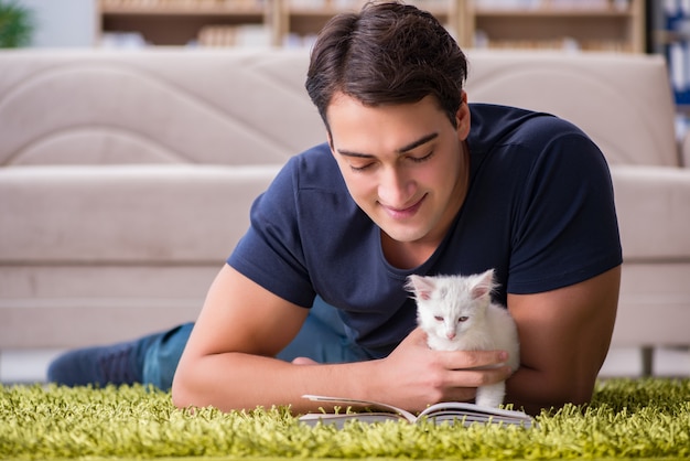 Jeune bel homme jouant avec un chaton blanc