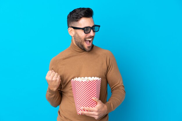 Jeune bel homme avec des lunettes 3d et tenant un gros seau de pop-corn tout en regardant de côté