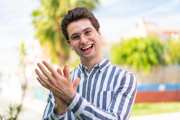 Jeune bel homme avec des lunettes et applaudissant