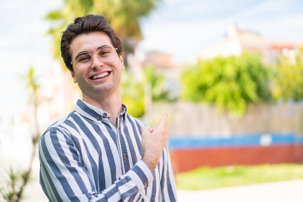 Jeune bel homme avec des lunettes et côté pointant