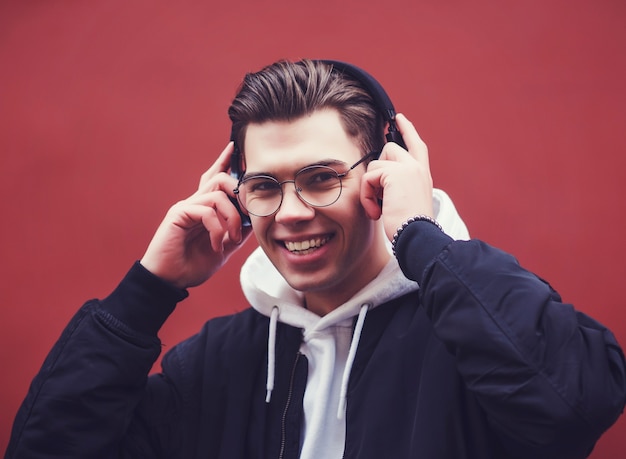 Jeune bel homme avec des lunettes, écouter de la musique dans des écouteurs