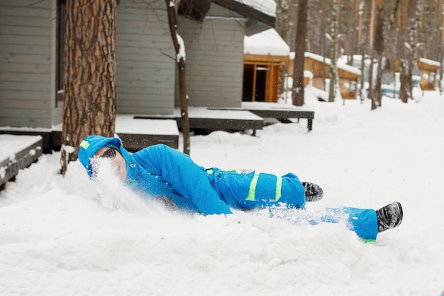 Jeune, bel homme à lunettes de soleil jette des boules de neige en hiver à l'extérieur