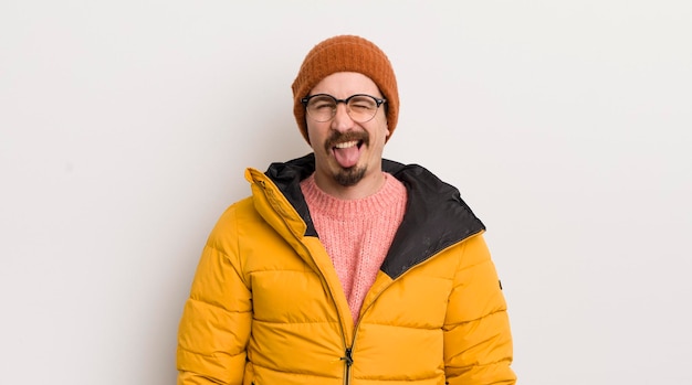 Jeune bel homme avec un manteau contre un mur blanc