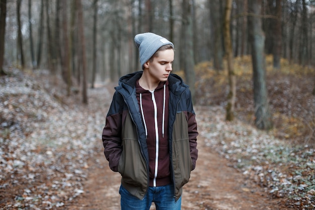 Jeune bel homme marchant dans la forêt d'automne