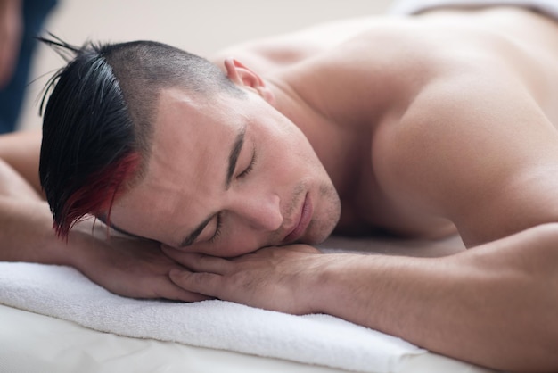 jeune bel homme a un massage relaxant dans le spa et le salon de bien-être
