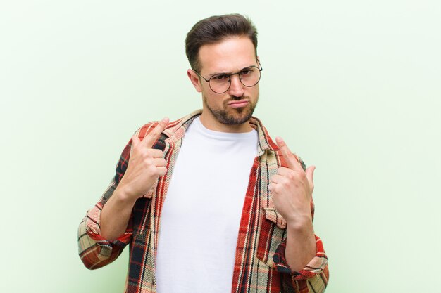 Jeune bel homme avec une mauvaise attitude à l'air fier et agressif, pointant vers le haut ou se moquant de signe avec les mains