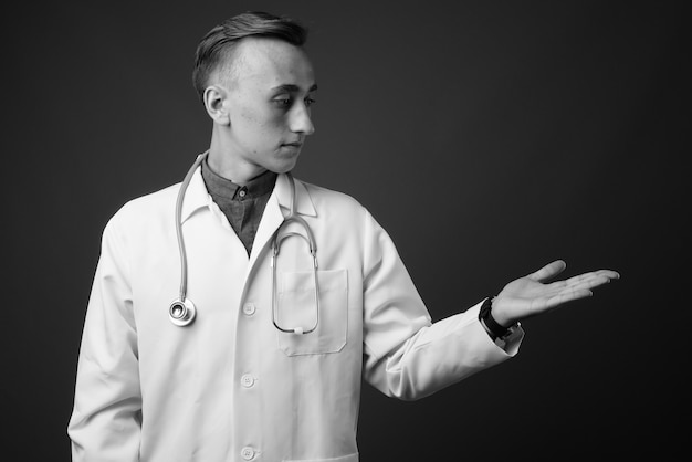 jeune bel homme médecin contre le mur gris. noir et blanc