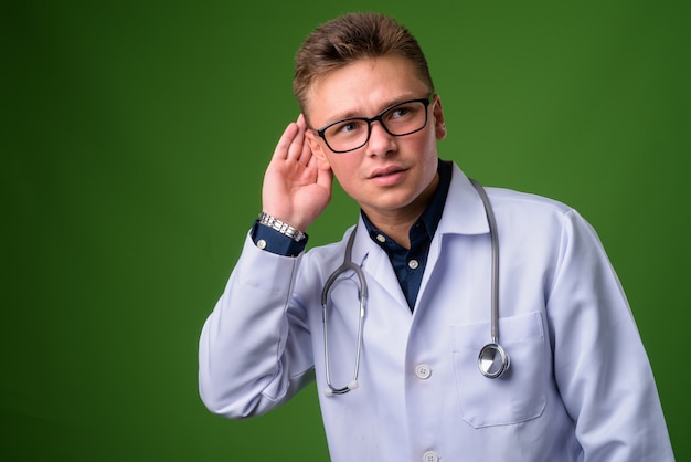 Jeune bel homme médecin sur fond vert