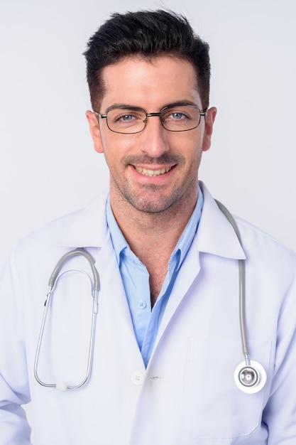 Jeune bel homme médecin portant des lunettes isolés contre le mur blanc