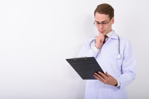 Jeune bel homme médecin portant des lunettes sur un mur blanc