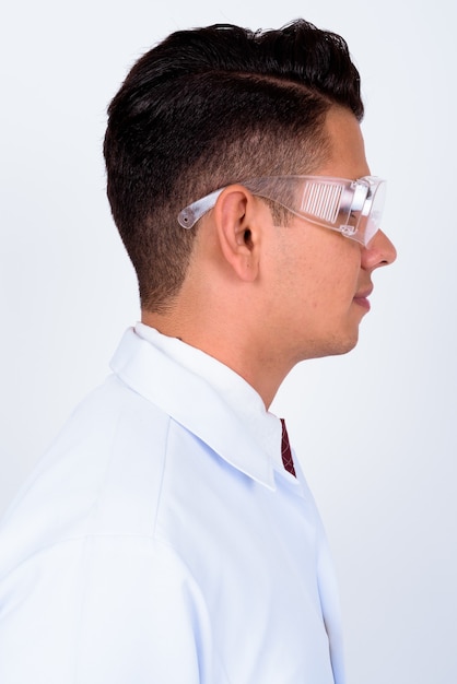 Jeune bel homme médecin en tant que scientifique portant des lunettes de protection sur blanc