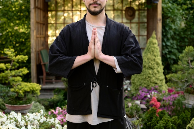 Photo jeune bel homme méditant dans le jardin de bonsaïs