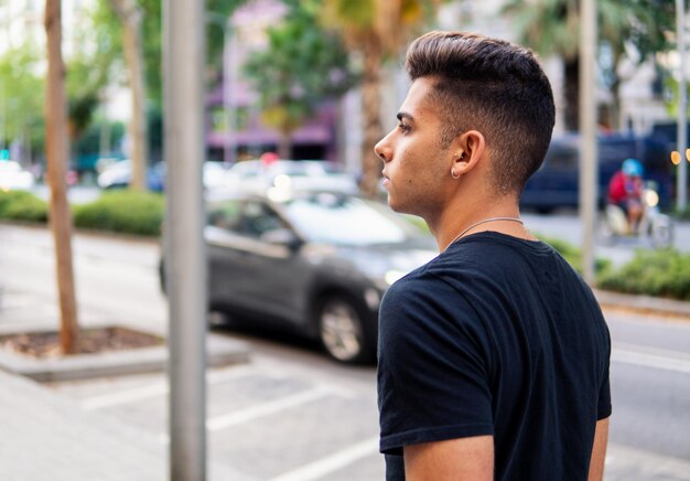 Jeune bel homme à la mode dans la rue de la ville moderne. Il semble heureux