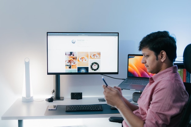 jeune bel homme moderne en tenue décontractée assis à table travaillant sur ordinateur portable