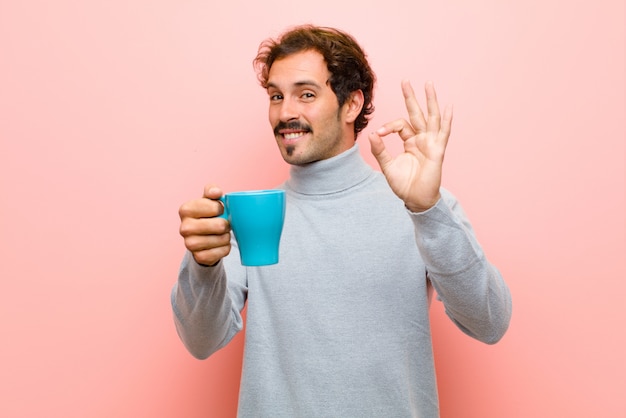 Jeune bel homme avec un mur plat tasse de café rose