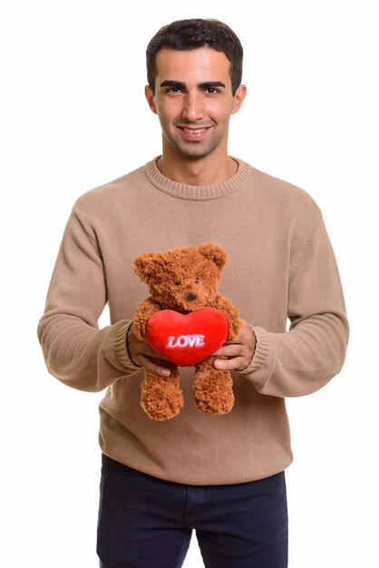 Jeune bel homme persan tenant un ours en peluche avec le symbole de l'amour