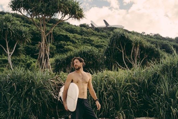 Jeune bel homme avec une planche de surf sur l'océan.