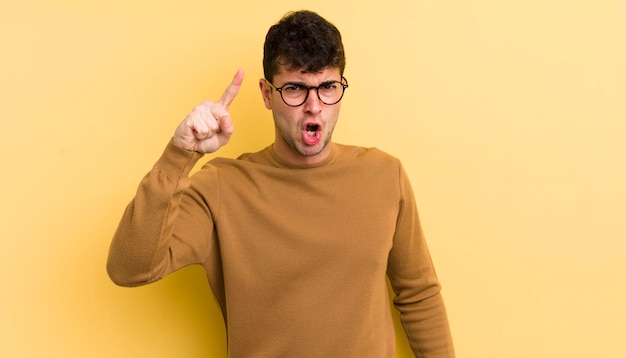 Jeune bel homme pointant vers la caméra avec une expression agressive en colère ressemblant à un patron fou furieux