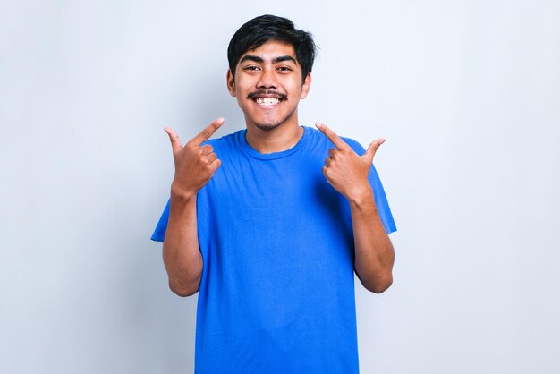 Jeune bel homme portant un pull décontracté debout sur un fond blanc isolé souriant montrant et pointant du doigt les dents et la bouche. Concept de santé dentaire.