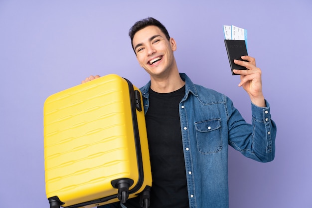 Jeune bel homme sur pourpre en vacances avec valise et passeport