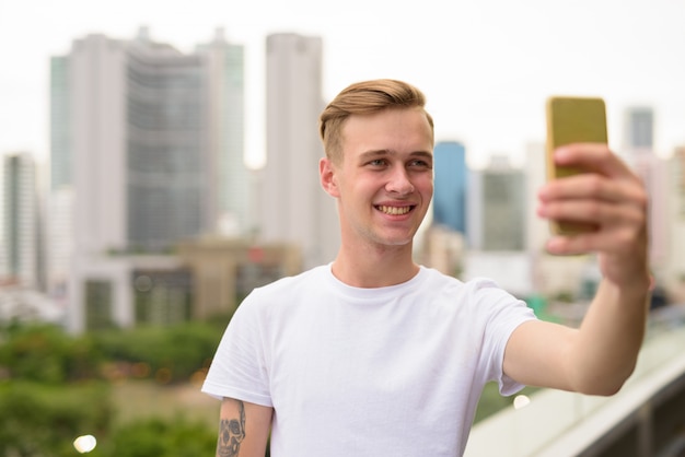 Jeune bel homme prenant selfie avec téléphone mobile