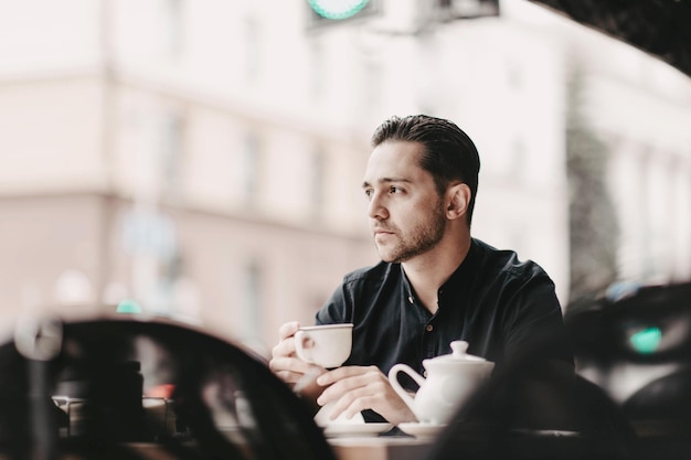 jeune bel homme prend son petit déjeuner et boit du café thé le matin sur la terrasse d'un restaurant