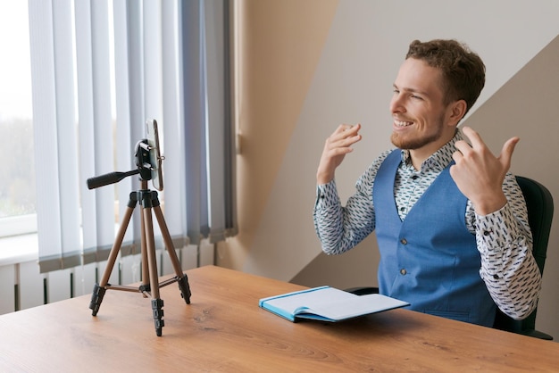 Jeune bel homme qui fait de la vidéo passe un appel vidéo en ligne en utilisant