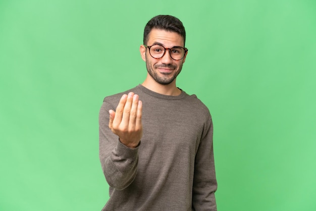 Jeune bel homme de race blanche sur fond isolé invitant à venir avec la main Heureux que vous soyez venu