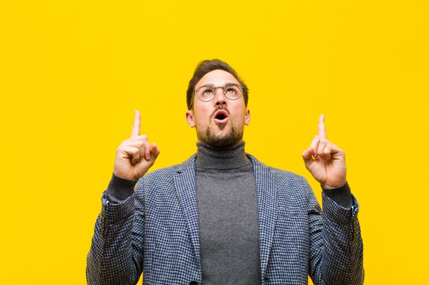 Jeune bel homme à la recherche de choqué, émerveillé et bouche bée