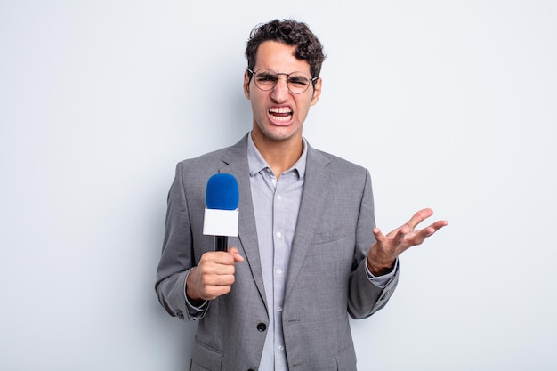 Jeune bel homme à la recherche de colère, agacé et frustré. présentateur avec microphone