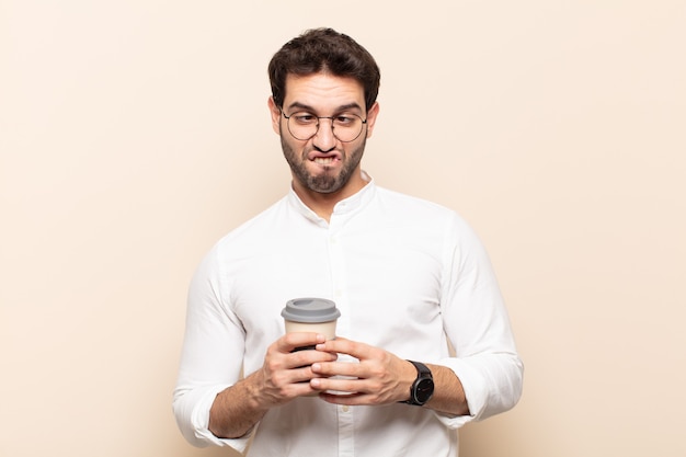 Jeune bel homme à la recherche de maladroit et drôle avec une expression idiote aux yeux croisés, plaisantant et s'amusant