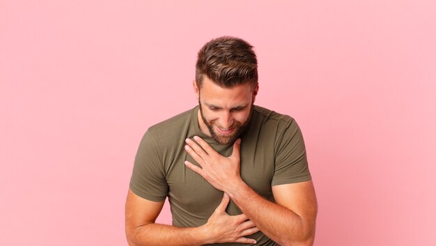 Jeune bel homme riant aux éclats d'une blague hilarante