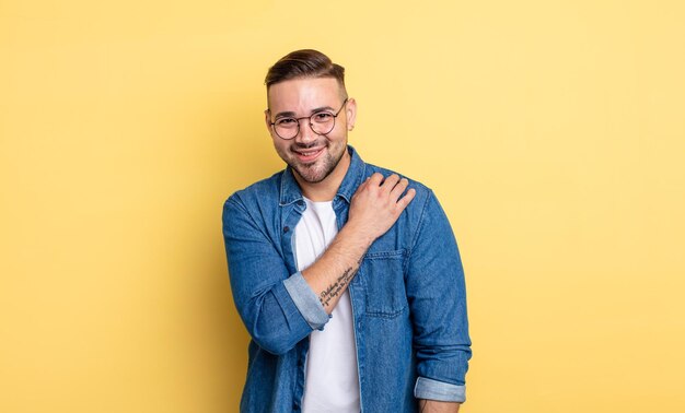 Jeune bel homme riant joyeusement et avec confiance avec un sourire décontracté, heureux et amical