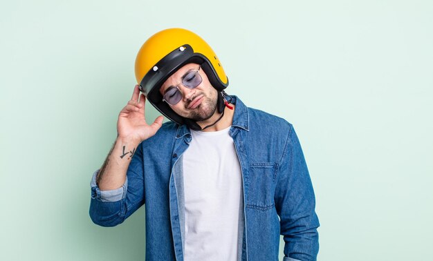 Jeune bel homme s'ennuyant, frustré et somnolent après une période fastidieuse. concept de casque de moto