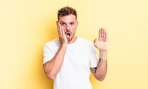 Jeune bel homme se sentant choqué et effrayé. concept de bandage à la main