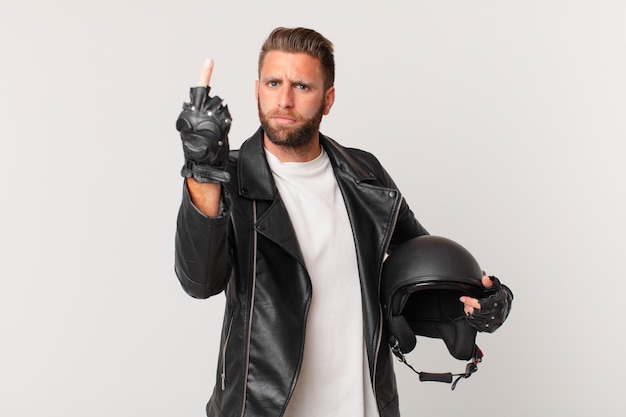 Jeune bel homme se sentant en colère, agacé, rebelle et agressif. concept de casque de moto