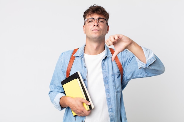 Jeune bel homme se sentant croisé, montrant les pouces vers le bas. concept d'étudiant universitaire