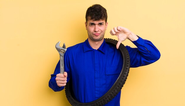 Jeune bel homme se sentant croisé les pouces vers le bas concept de réparateur de vélo