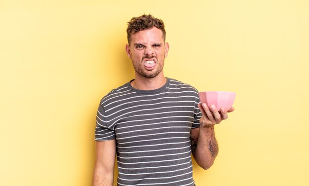 Jeune bel homme se sentant dégoûté et irrité et la langue sur le concept de bol vide