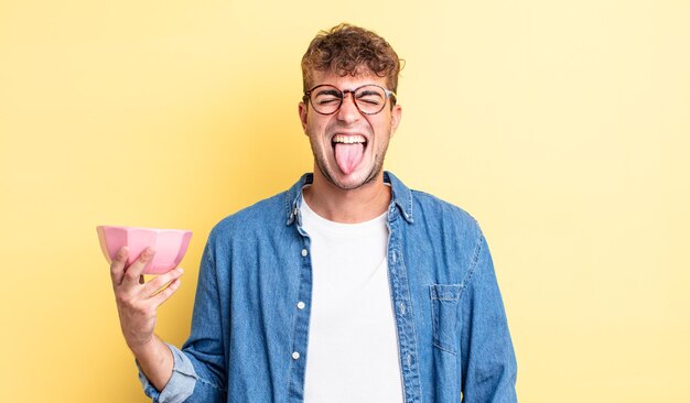 Jeune bel homme se sentant dégoûté et irrité et tirer la langue. concept de bol vide