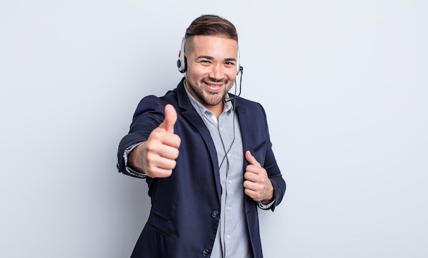 Jeune bel homme se sentant fier, souriant positivement avec les pouces vers le haut. concept de télémarketing