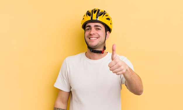 Jeune bel homme se sentant fier de sourire positivement avec le concept de vélo pouce en l'air