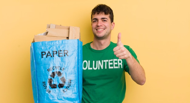 Jeune bel homme se sentant fier de sourire positivement avec les pouces vers le haut