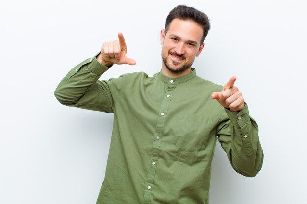 Jeune bel homme se sentant heureux et confiant, pointant vers la caméra avec les deux mains et riant, vous choisissant