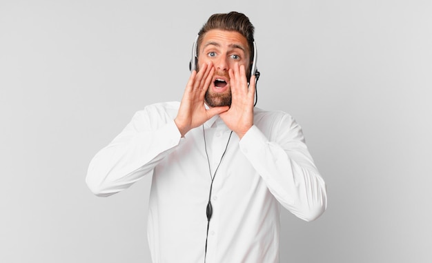 Jeune bel homme se sentant heureux en donnant un grand cri avec les mains à côté de la bouche concept de télémarketing