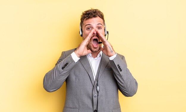 Jeune bel homme se sentant heureux, donnant un grand cri avec les mains à côté de la bouche. concept de télévendeur