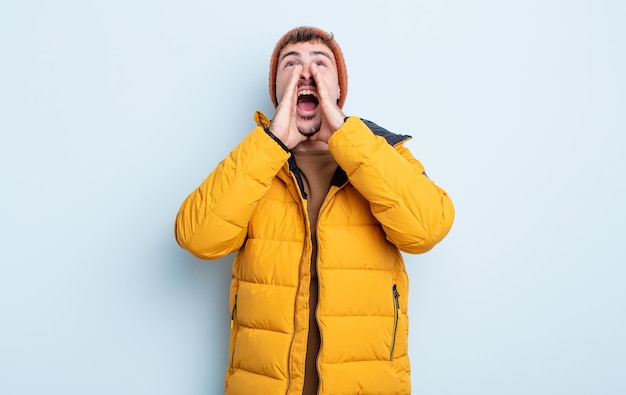 Jeune bel homme se sentant heureux, donnant un grand cri avec les mains à côté de la bouche. notion d'hiver